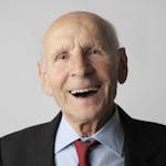 A smiling elderly man in a suit and tie, conveying happiness and wisdom.